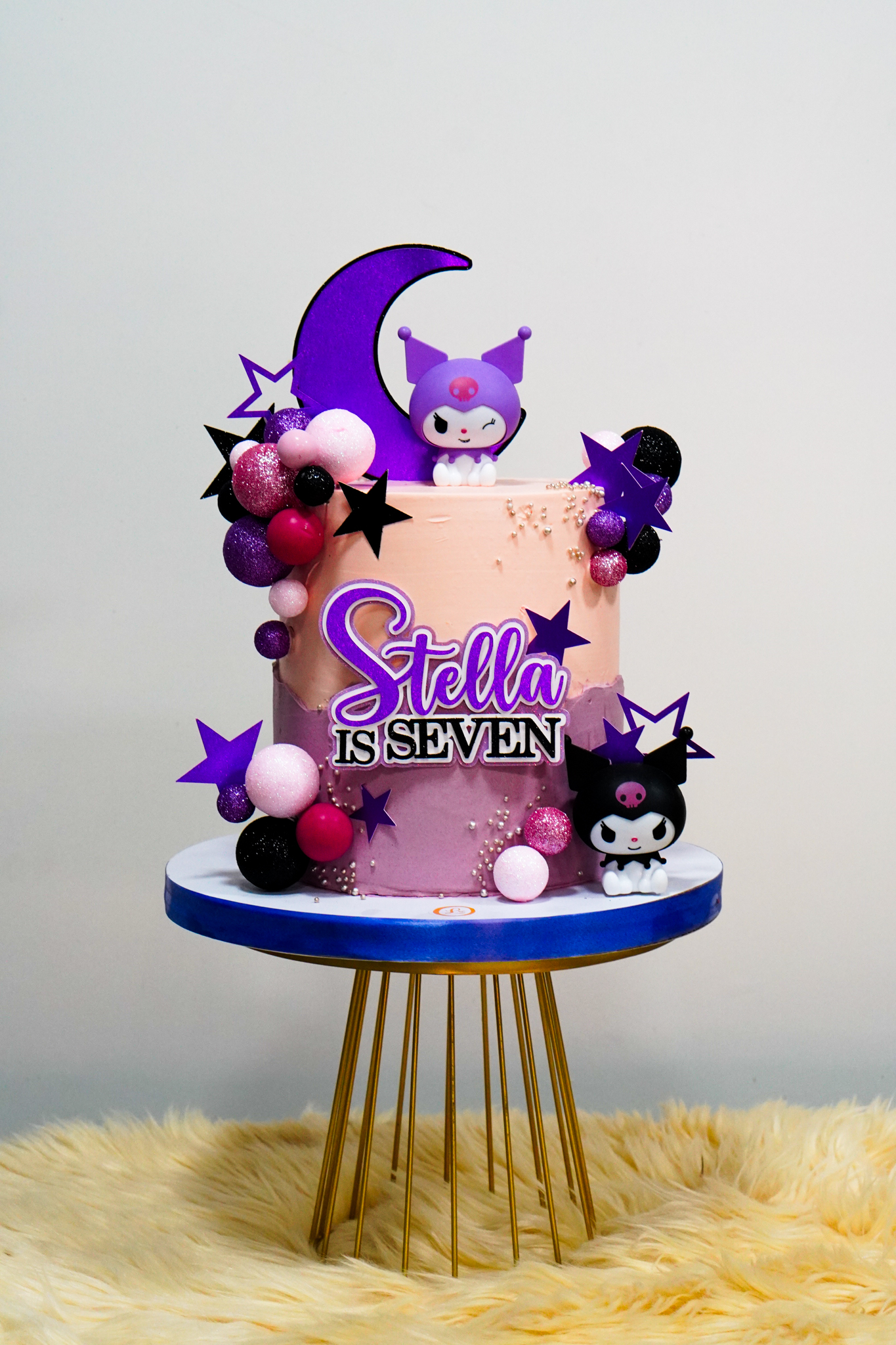 Kuromi-themed purple and pink birthday cake with star decorations, moon topper, and balloon clusters