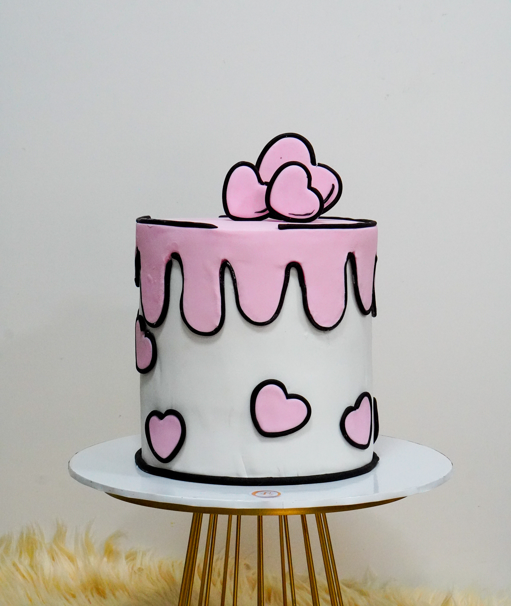 Cartoon-style cake with white base, pink drip effect, and pink heart decorations outlined in black